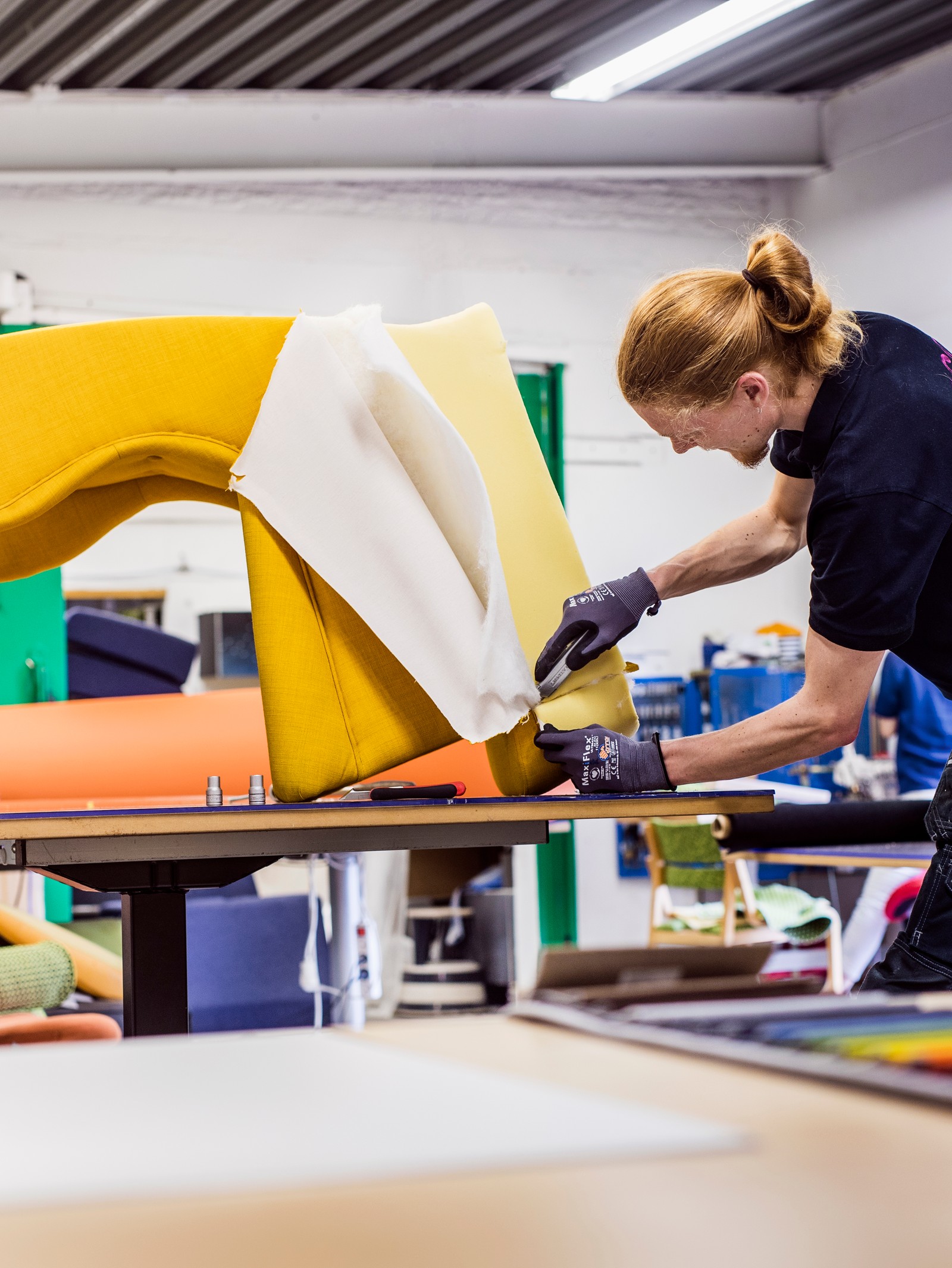 IKEA zaposleni u crnoj majici i radnim rukavicama ponovo tapecira fotelju svetložutom tkaninom.