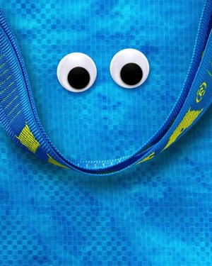 Eine blaue FRAKTA Tasche mit Henkel, auf dem sich zwei Augen bewegen.