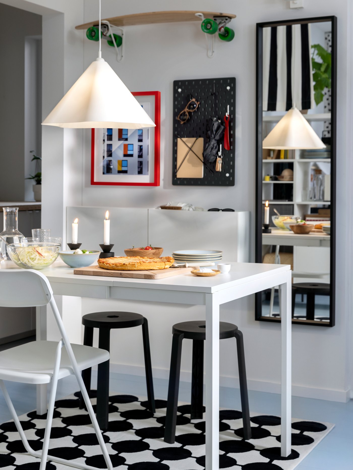 Une table extensible VIHALS, une chaise pliante VIHALS et des tabourets sont posés sur un tapis VÄNDPLATS sous une lampe suspendue blanche ZEBRASÄV.