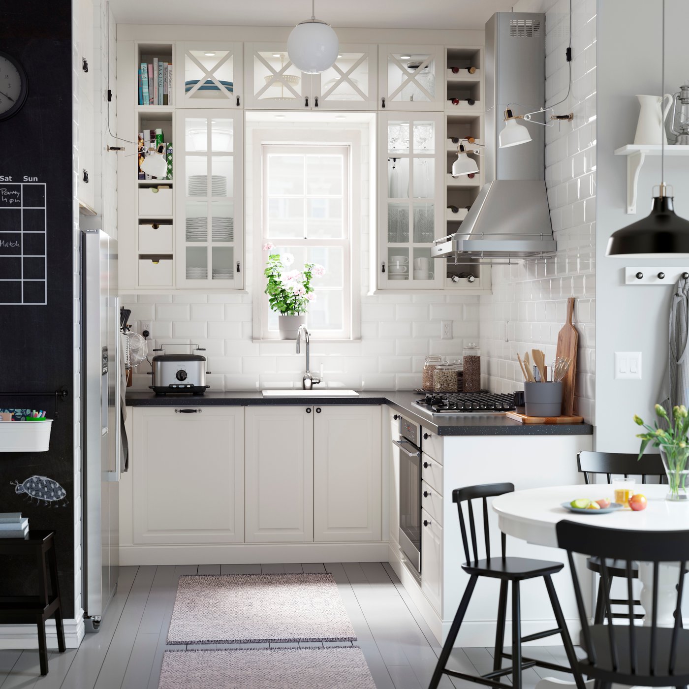 A kitchen with off-white glass-doored cabinets arranged around a window and a black mineral effect worktop.