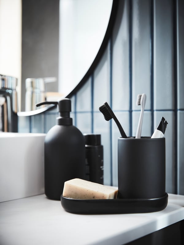 Distributeur de savon et porte-brosses à dents EKLON noirs posés sur le lavabo 