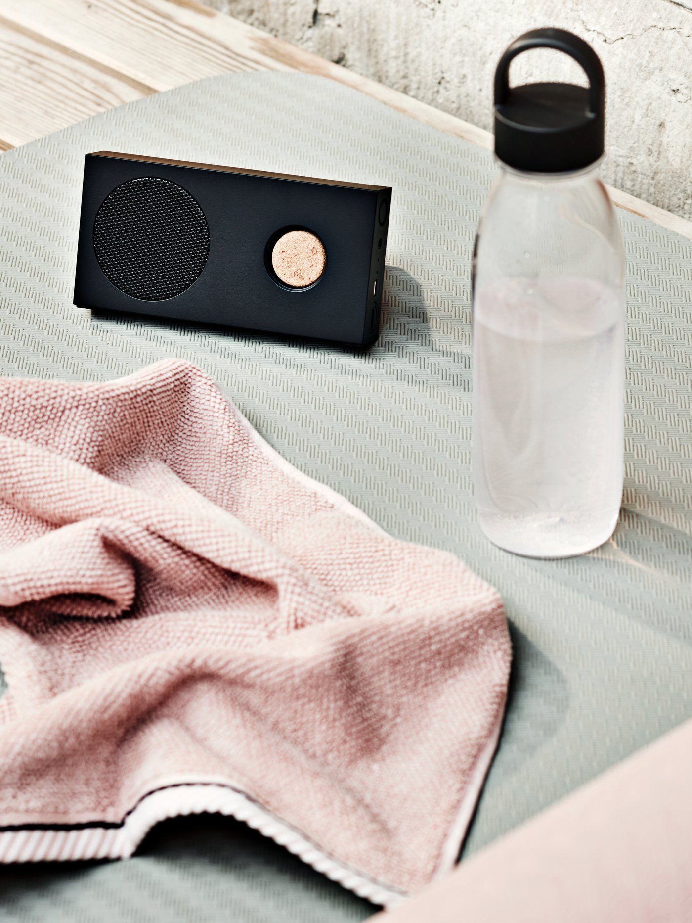 An IKEA 365+ water bottle stands near an ENEBY portable Bluetooth speaker and a light pink VIKFJÄRD guest towel.