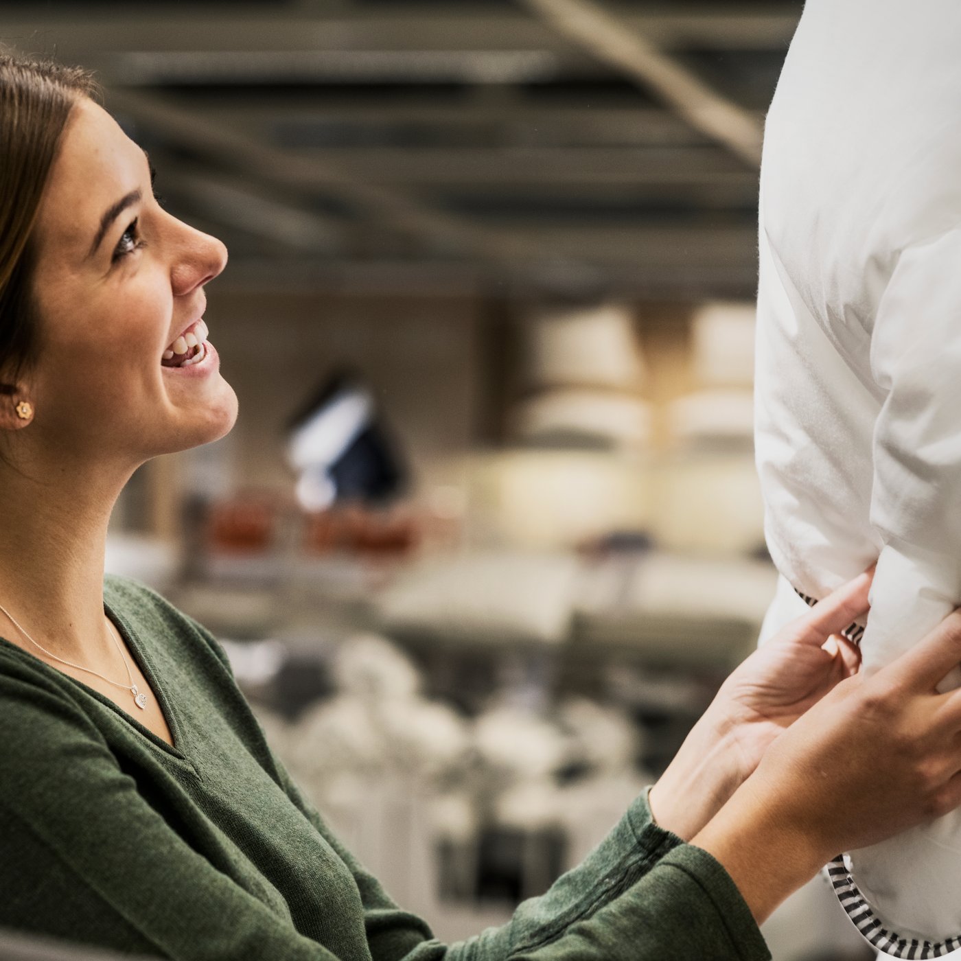 Kobieta w zielonej bluzce ogląda kołdrę  w sklepie IKEA.