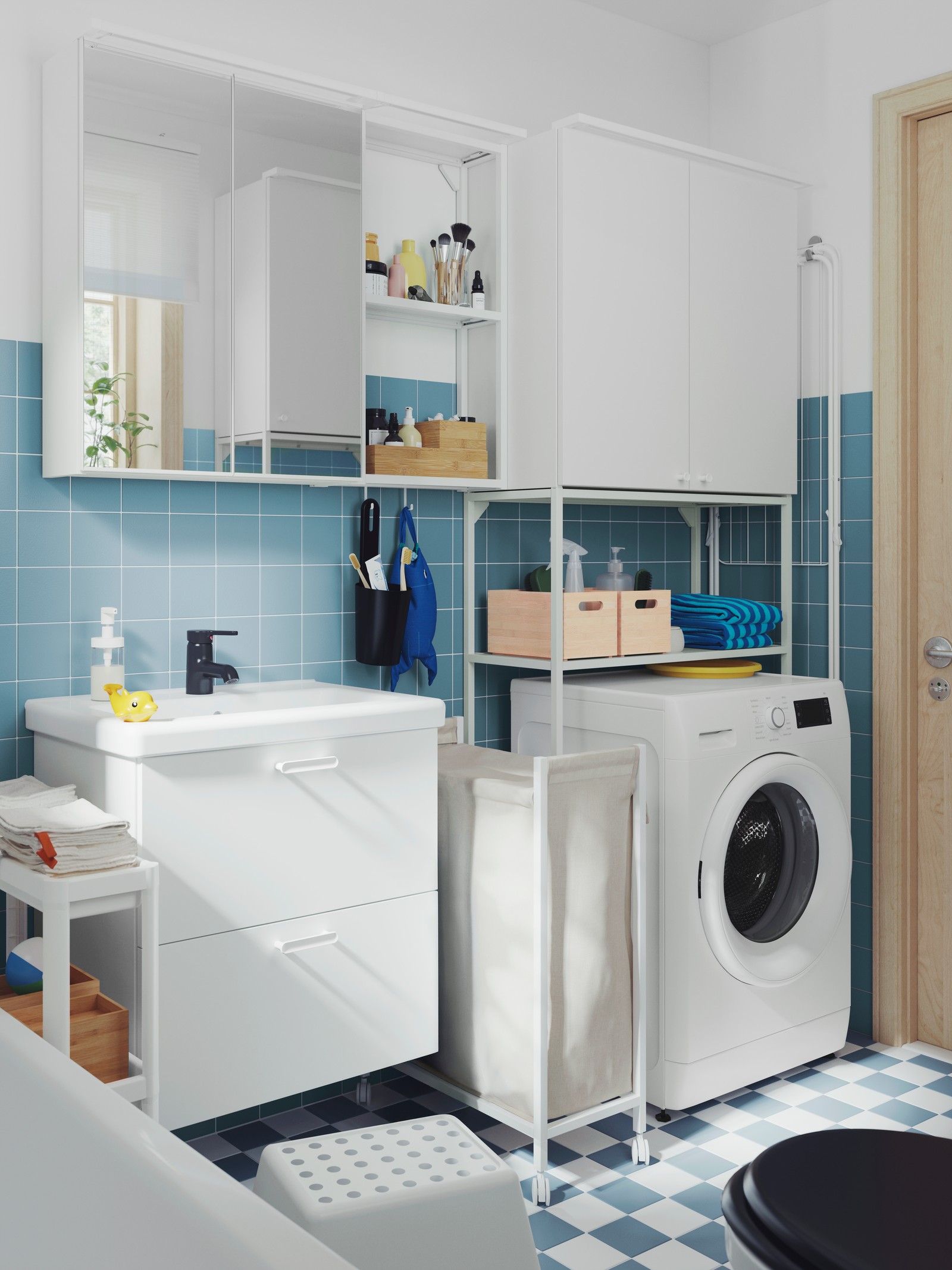 Et hvitt ENHET servantskap, et speilskap, et høyskap og ei hvit VESKEN hylle med hjul i et lite bad med blå fliser.