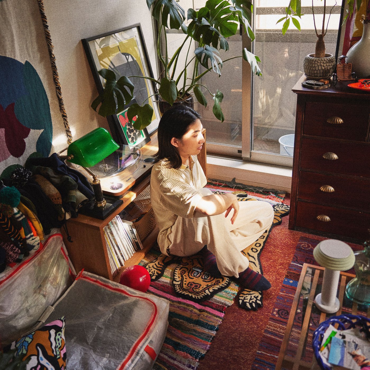 거실 바닥에 앉아 있는 한 남성 주변으로 가구가 빼곡하게 배치된 모습.