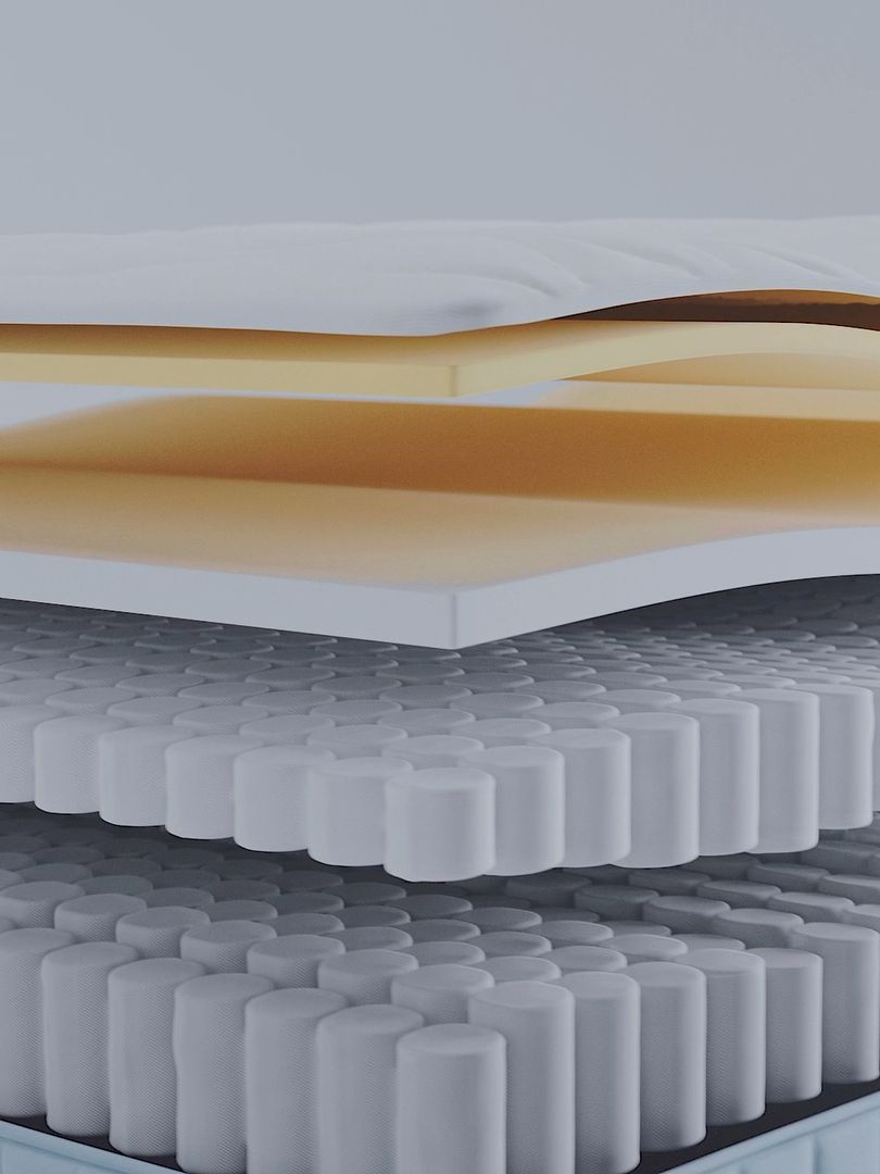 Section of a mattress showing layered foam and pocketed coil springs.
