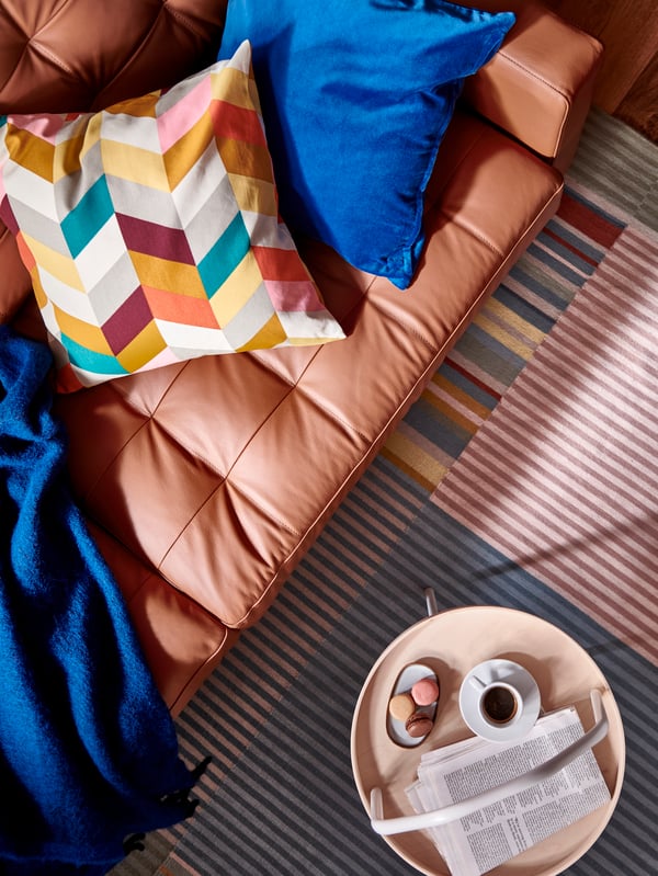 A LANDSKRONA sofa, with a KLIPPOXEL throw, a HANNELISE cushion and a cushion with a blue SANELA cover, stands on a rug.