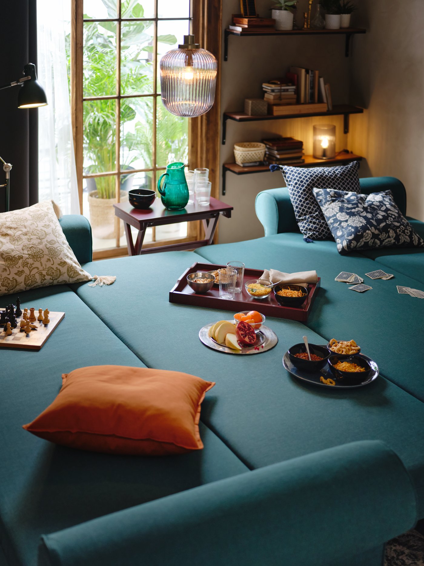 A cosy, small living room with a petrol blue sofa bed and a SOLKLINT pendant lamp.