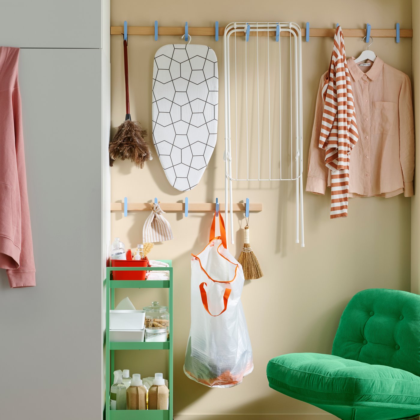 A space-saving laundry corner, with laundry equipment on a NISSAFORS trolley and a hook rack with PÄRKLA laundry bag.