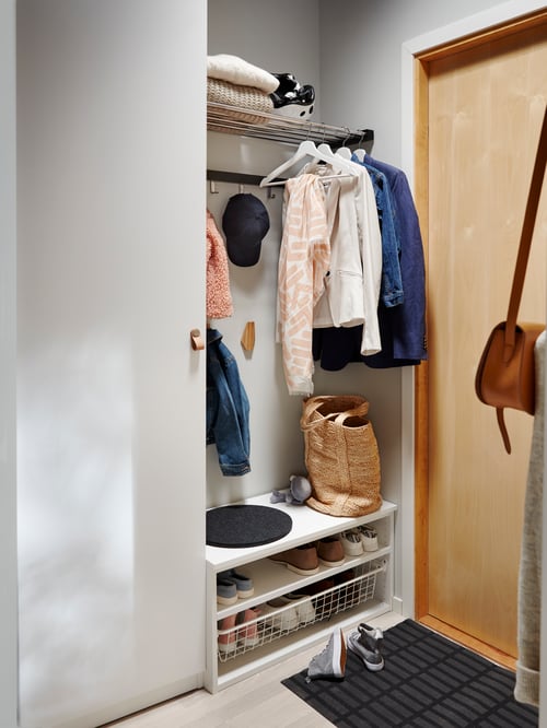 Hallway with a closed wardrobe, a door mat on the floor, several hooks, a shoe storage unit, a hat and clothes rack.