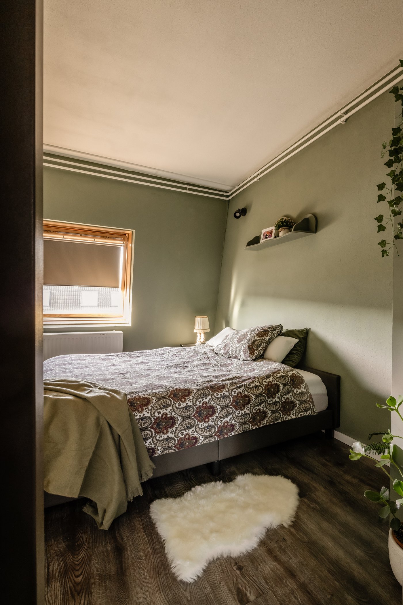 Slaapkamer met groene muren. Op de grond ligt een pluizig ULLERSLEV vloerkleed.