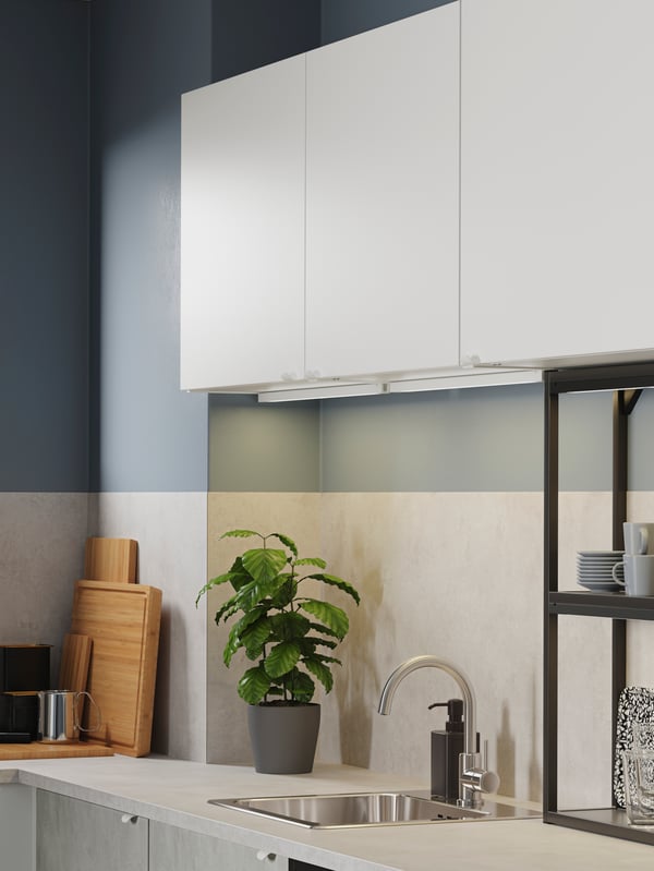Gros plan sur une cuisine blanche avec un mur gris