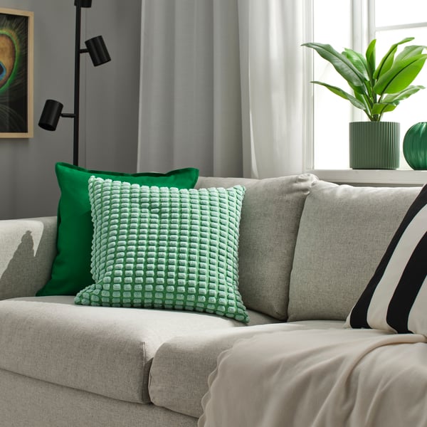 A light green SVARTPOPPEL cushion cover