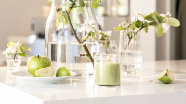 An Apple/light green LÖVSKOGSLUND scented candle in glass
