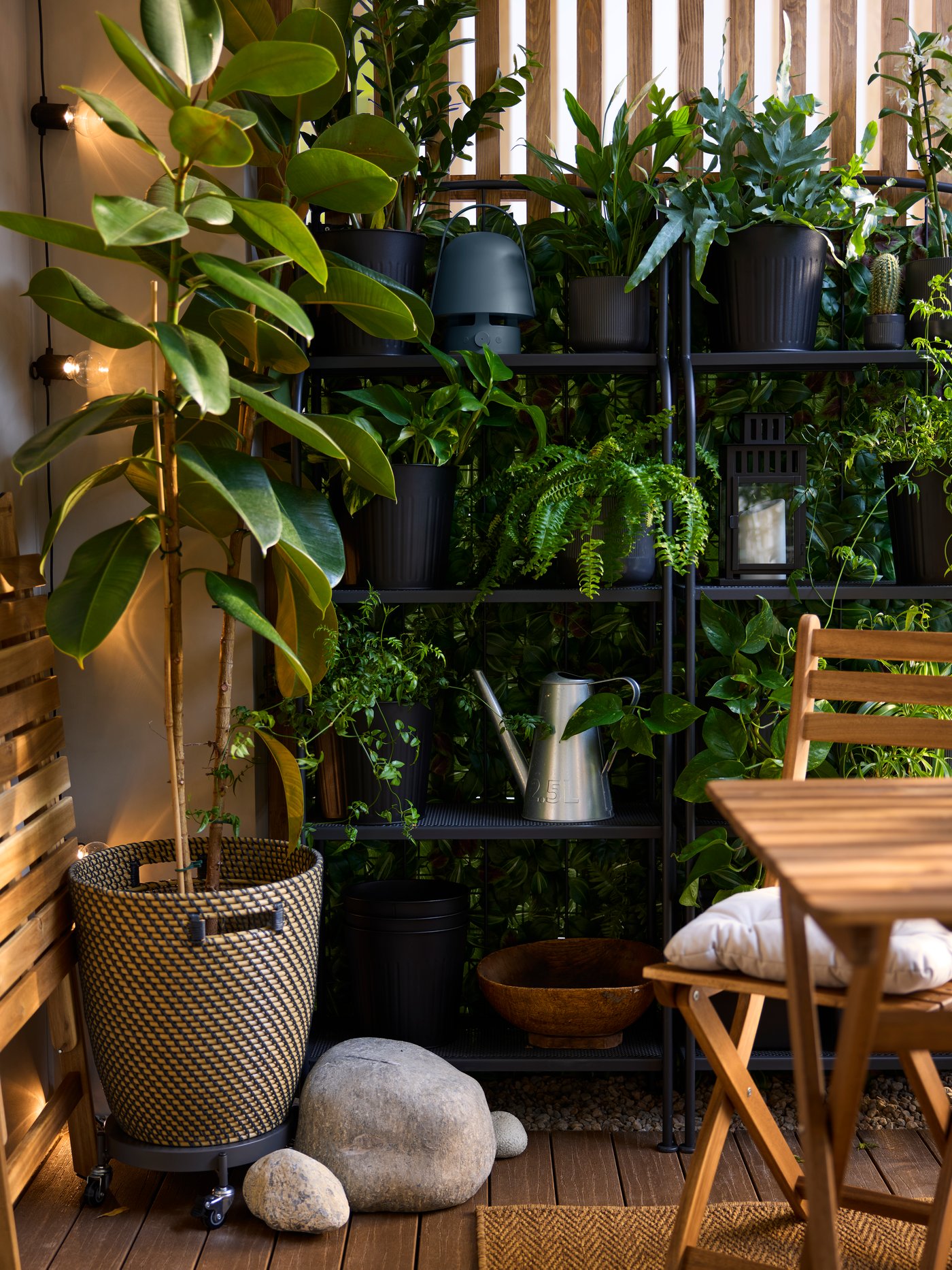 A balcony’s dividing wall has wall-mounted in/outdoor FEJKA artificial plants in green lilac, partly visible behind shelving.