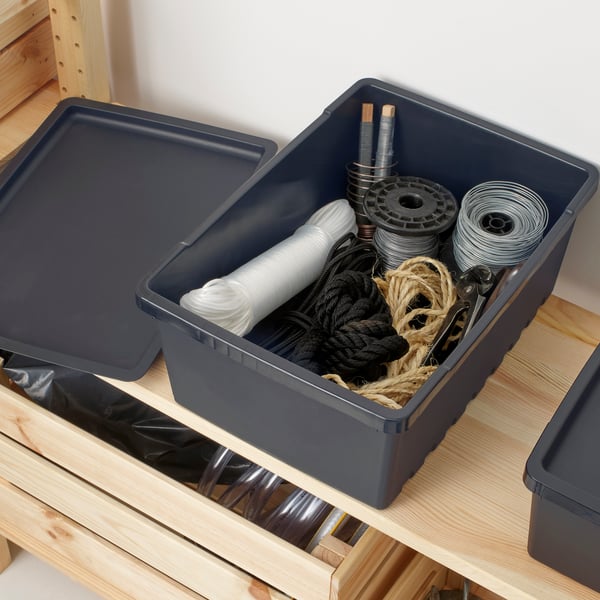 Geöffnete schwarze Aufbewahrungsbox mit Kabeln, Seilen und Bastelzubehör auf Holzregal