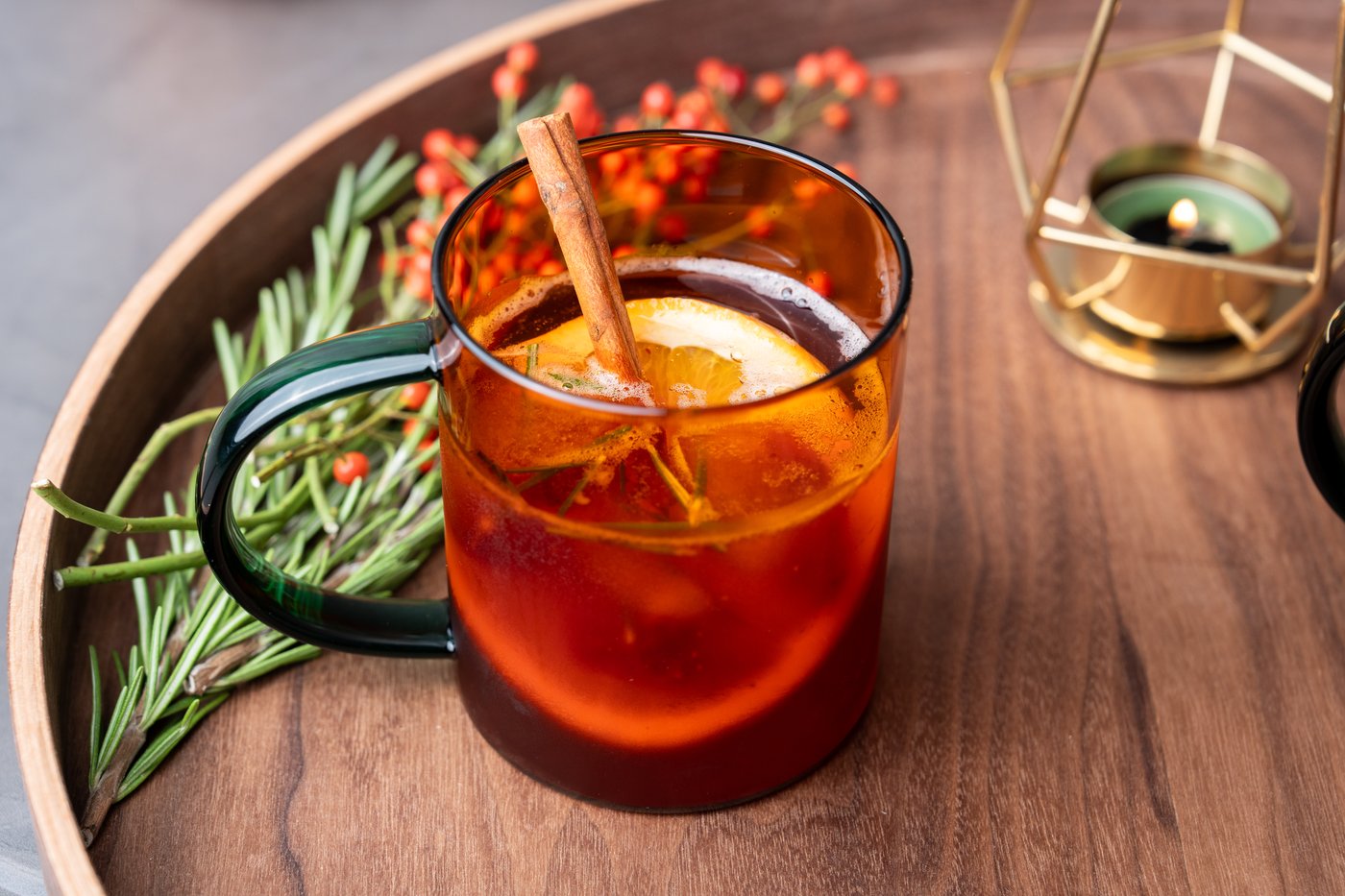 Sparkling Lingonberry Punsch in einem roten Glas auf einem Serviertablett aus Holz angerichtet.