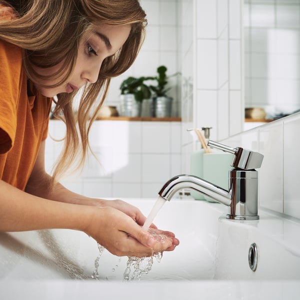 Una ragazzina chinata su un lavabo mentre si sta lavando le mani.