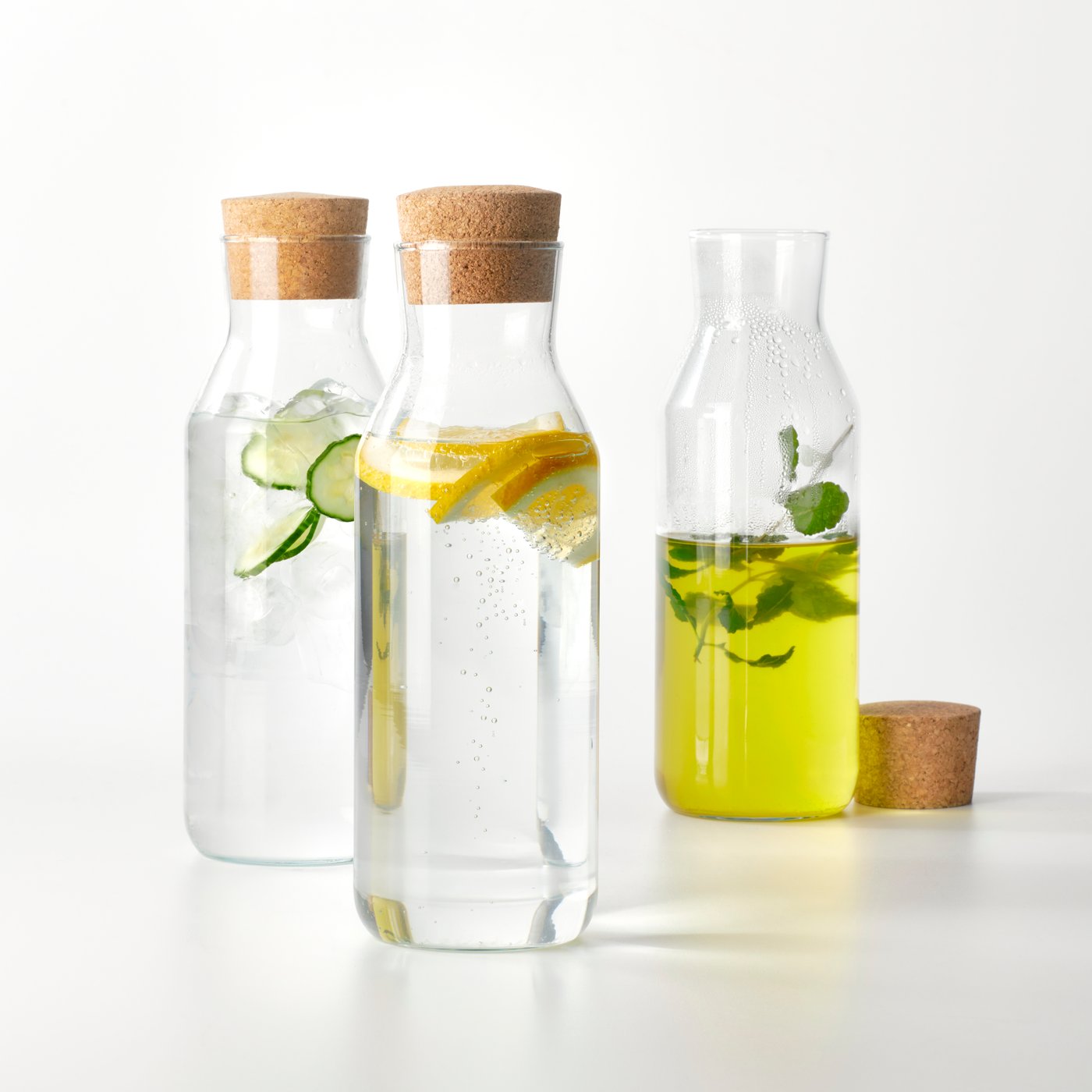 Tri IKEA 365+ staklene karafe s plutenim čepom. Jedna sadrži vrući čaj, druga hladnu ledenu vodu, a treća gaziranu vodu.