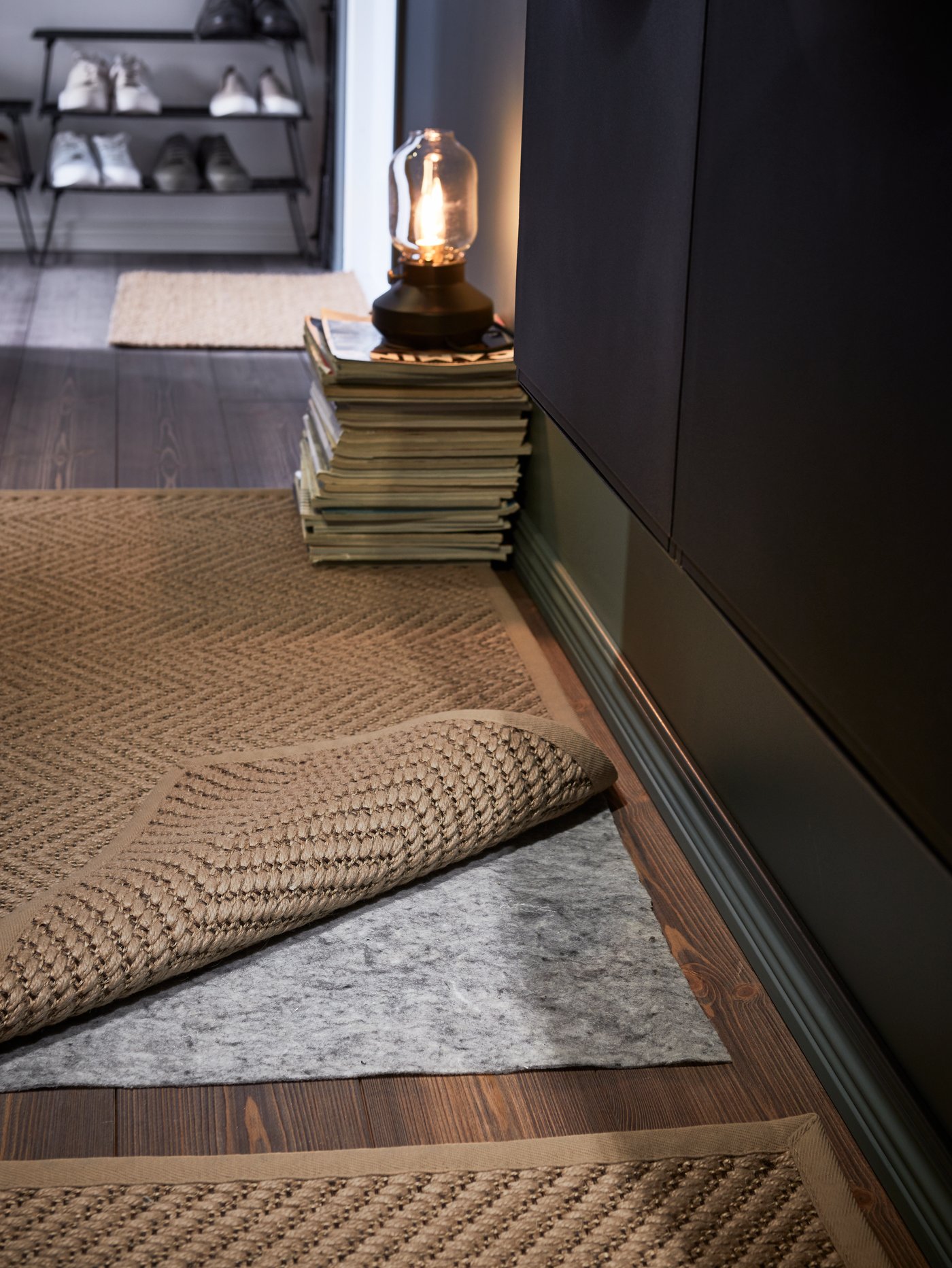 Un recibidor moderno con una alfombra plana rectangular con una base antideslizante y una lámpara de mesa gris.
