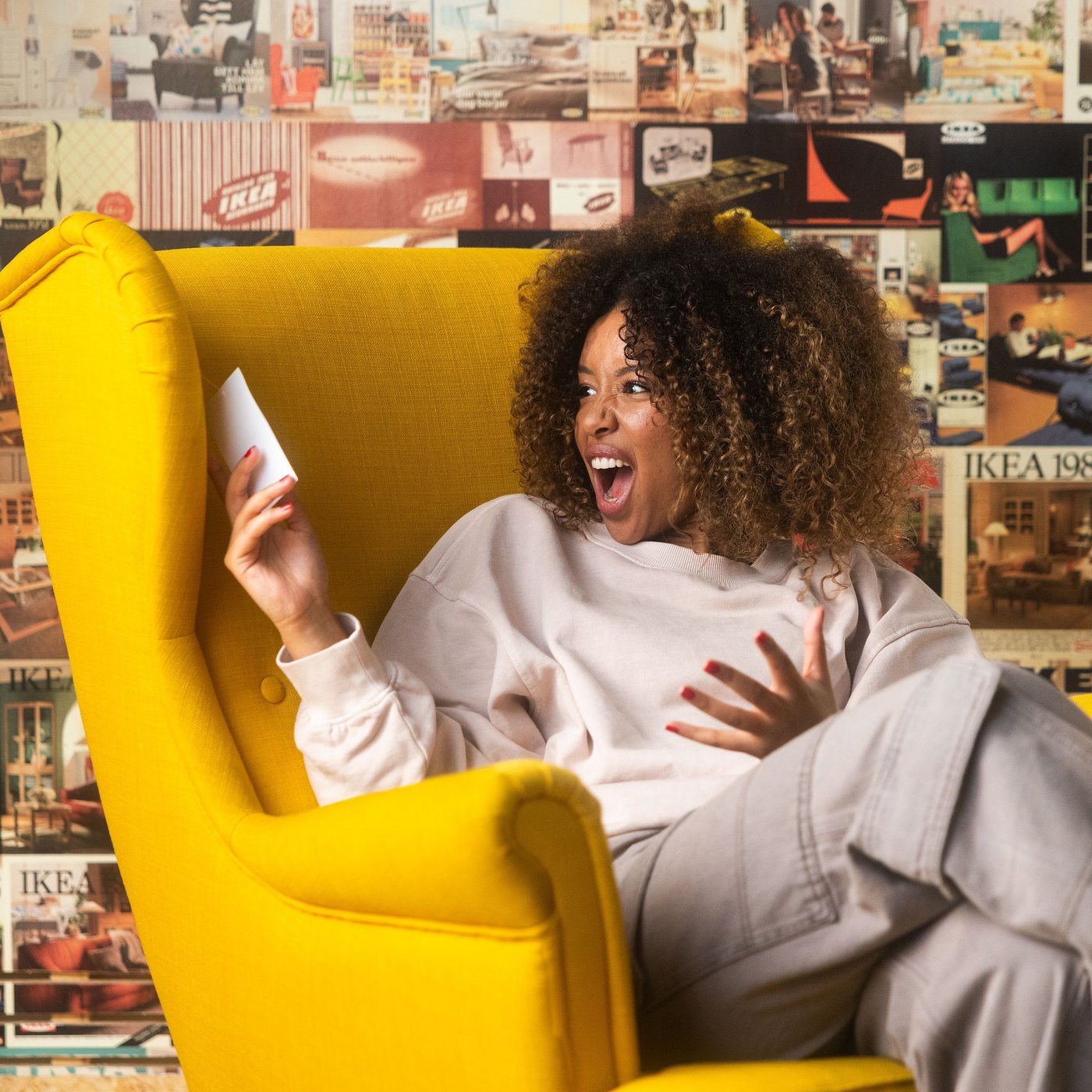 Nainen istuu keltaisessa nojatuolissa ja katsoo tuotteen hintalappua. 