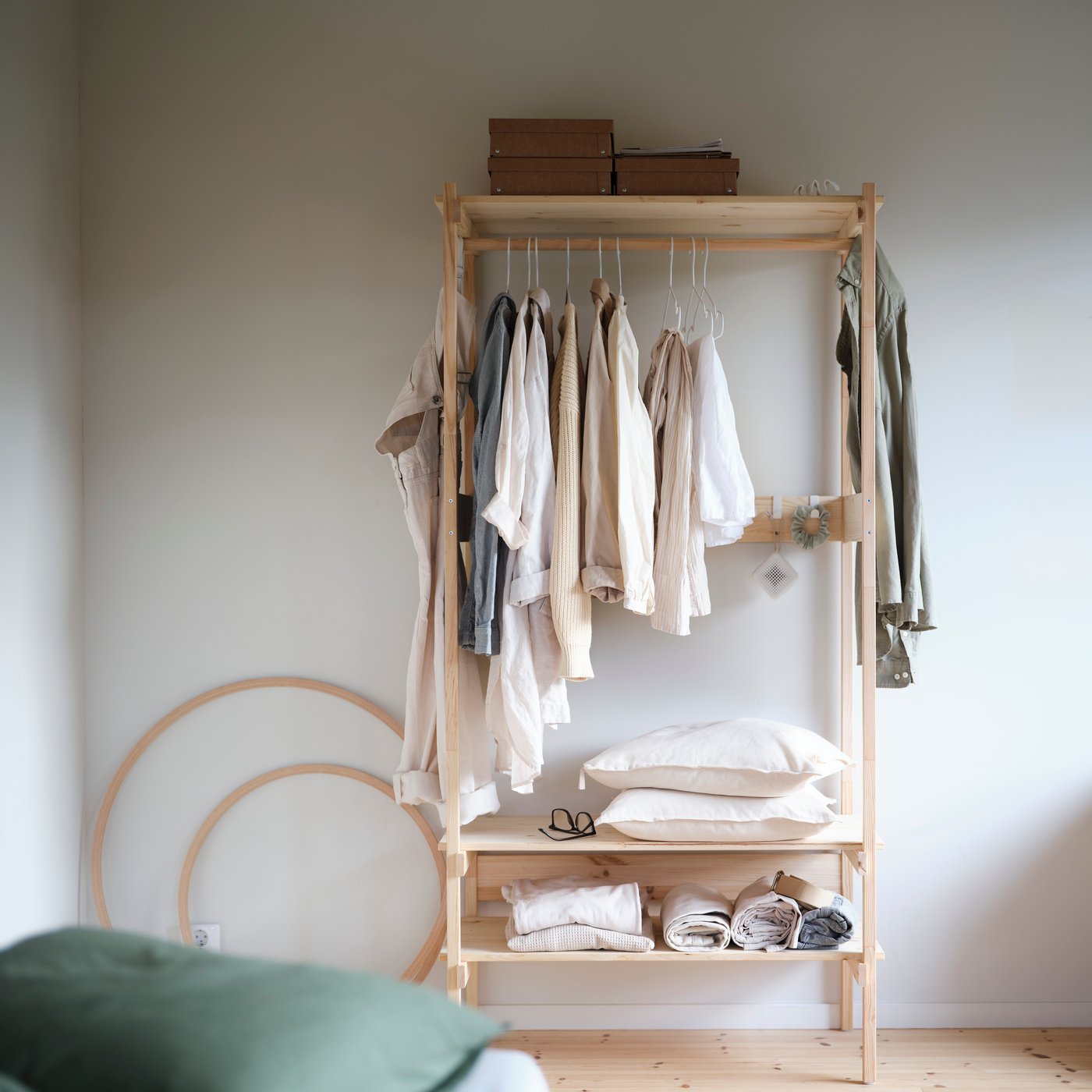 KRONÖREN öppen garderob i furu med hängande kläder och korgar på hyllor i ett lugnt och organiserat sovrum.