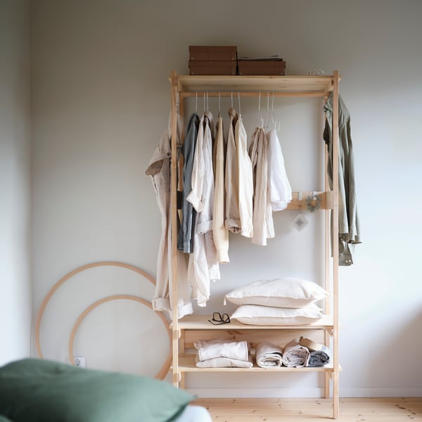 KRONÖREN open wardrobe in pine with hanging clothes and baskets on shelves in a calm, organised bedroom space.