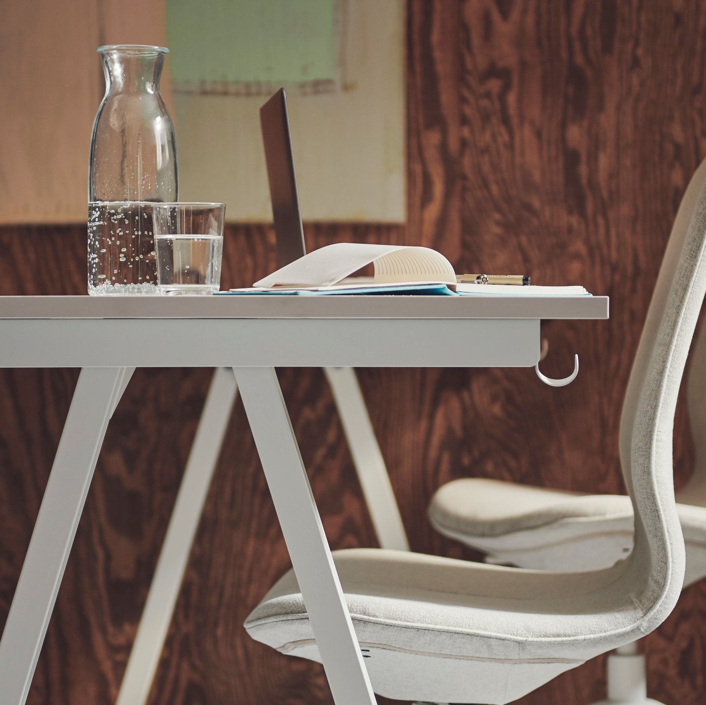 Two white-and-beige LÅNGFJÄLL office chairs placed side by side by a white TROTTEN desk by a brown wall.