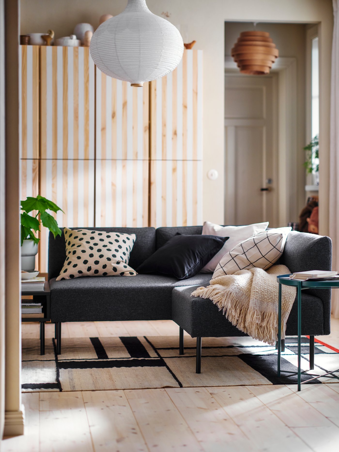 Modular LILLEHEM seating stands in a living room on a RASTPLATS rug in front of some IVAR storage with stripes painted on it.