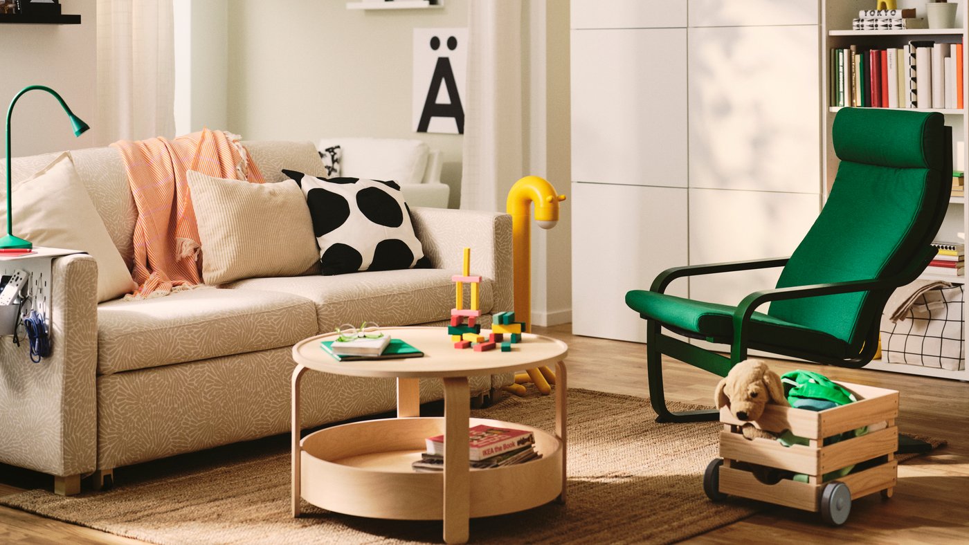 A living room features a light beige/white SALTSJÖBADEN 2-seat sofa-bed made from Vittangi. Decorative cushions and a table.