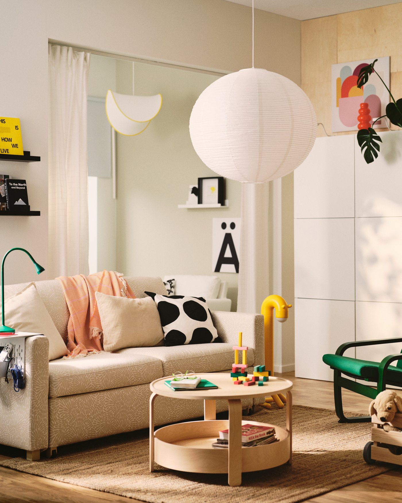 A living room features a light beige/white SALTSJÖBADEN 2-seat sofa-bed made from Vittangi. Decorative cushions and a table.