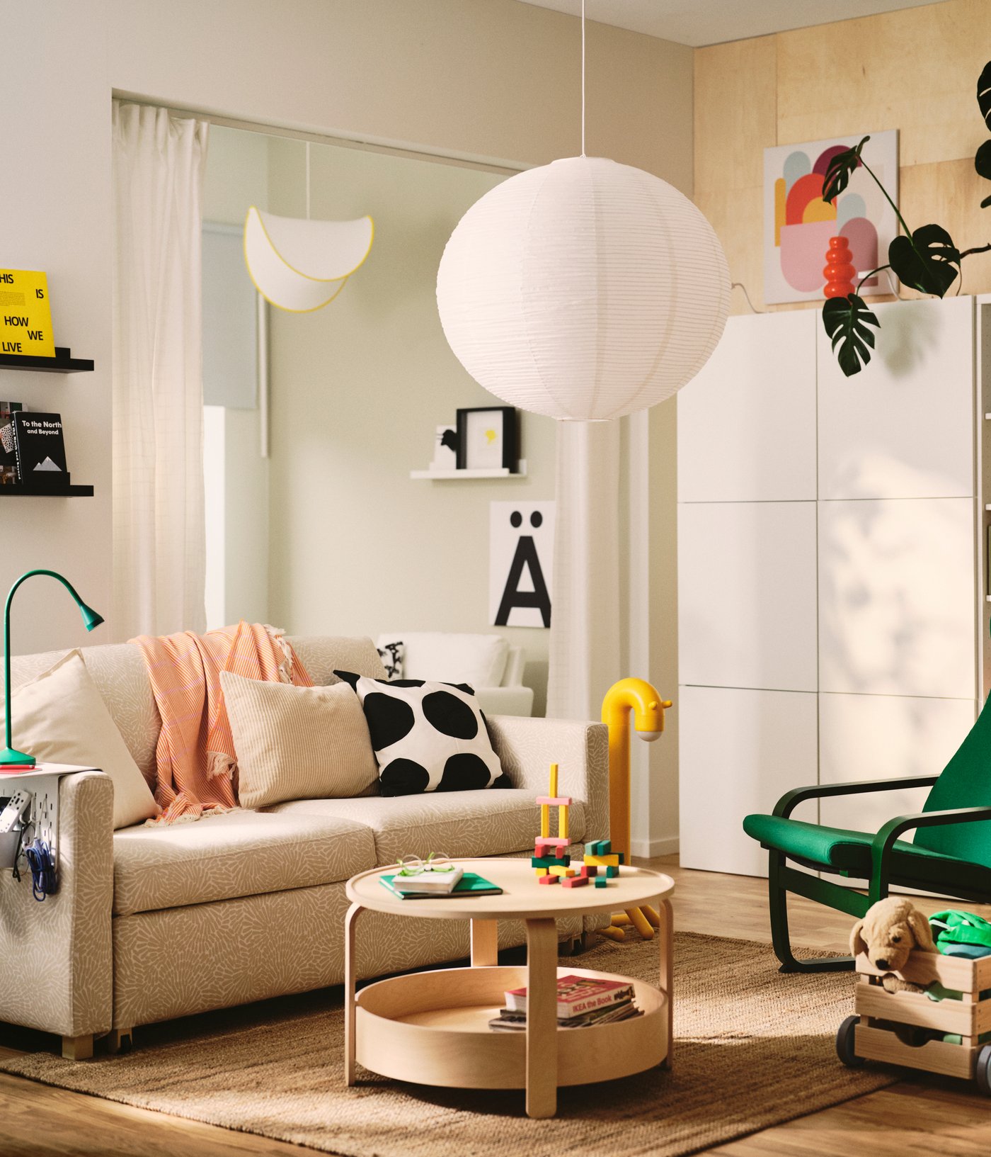 A la sala d'estar hi ha un sofà llit SALTSJÖBADEN de color beix clar/blanc de dues places de Vittangi. Una taula i coixins decoratius.
