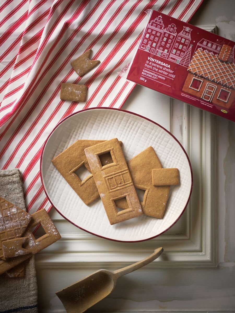 A selection of VINTERSAGA gingerbread house pieces placed on a white VINTER 2020 plate with red rimmed edges.