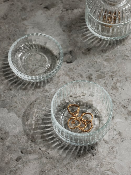 Două containere SILVTJÄRN cu bijuterii în interior, așezate pe un blat, într-un decor modern de sufragerie. 