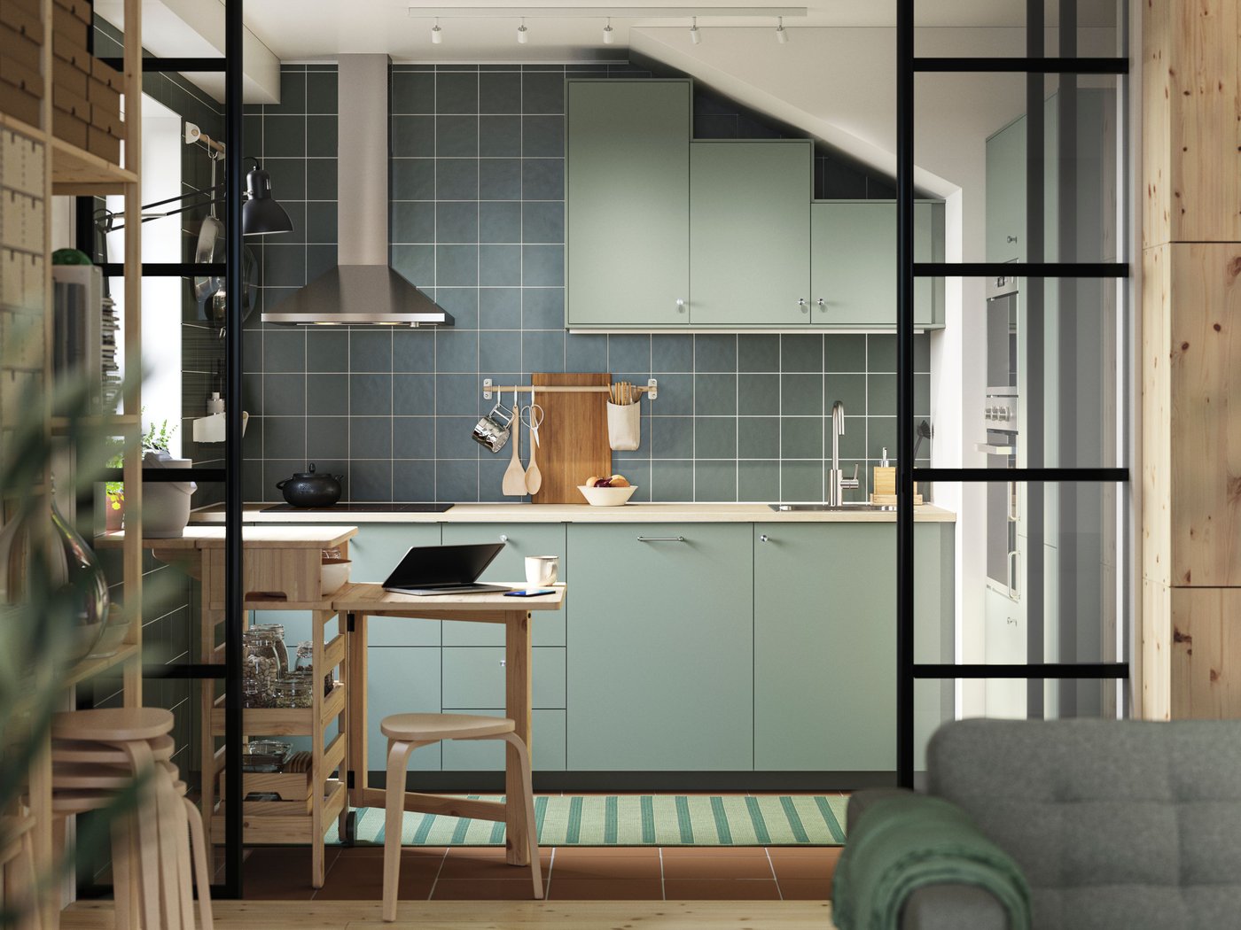 Une cuisine verte en L est équipée de façades NICKEBO gris vert et d'une table mobile RESARÖ à abattant avec rangement et quelques tabourets.