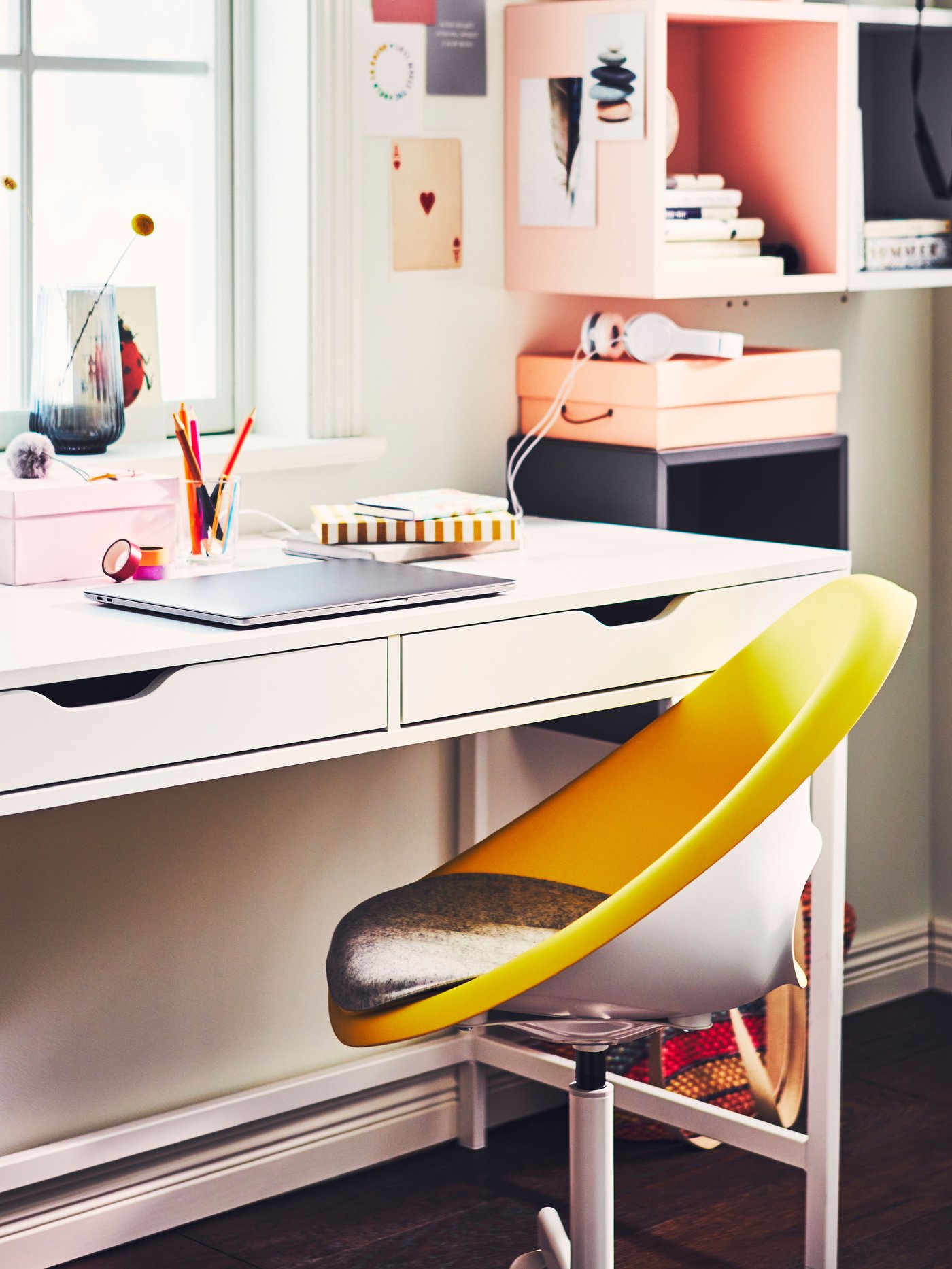 Un escritorio IKEA con dos cajones y en frente una silla de escritorio amarilla.