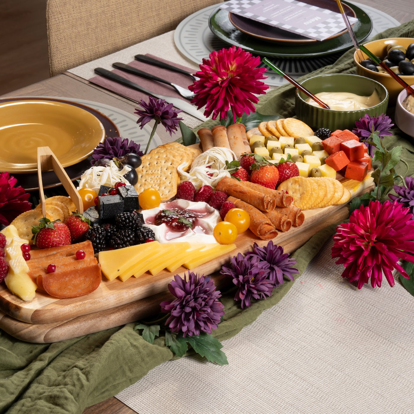 Cheese and charcuterie platter displayed on a dining table for a social gathering.