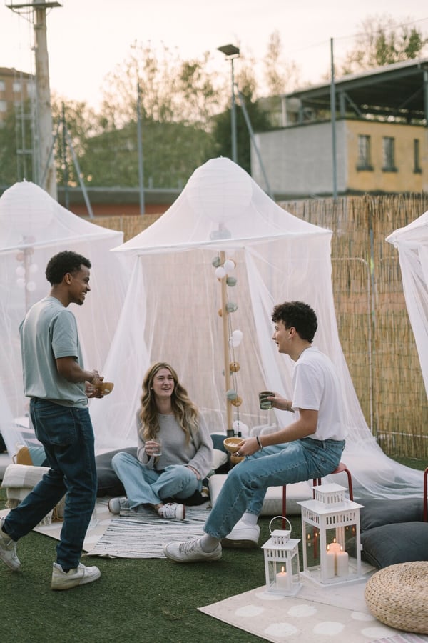 Tre persone che parlano in un ambiente esterno allestito con lanterne BORRBY, luci edecorative, tappeti e tende SOLIG.