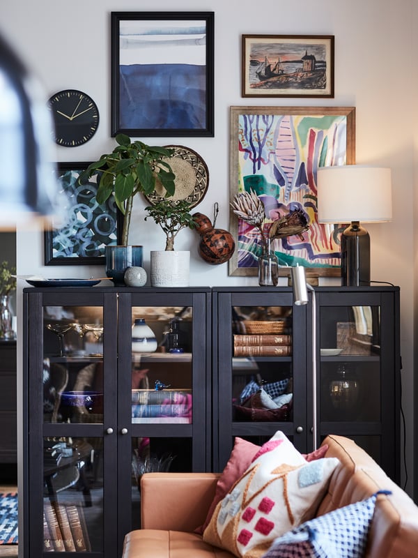 A grey HAVSTA storage combination is filled with decorative items, books, rattan baskets, vases and dried flowers.