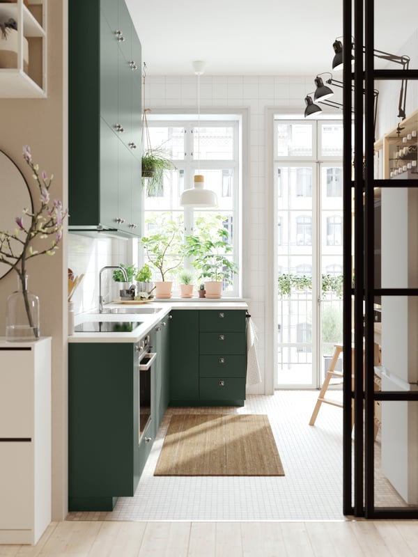 A kitchen with deep green kitchen fronts, a white marble effect/laminate worktop and a white/birch BUNKEFLO pendant lamp.