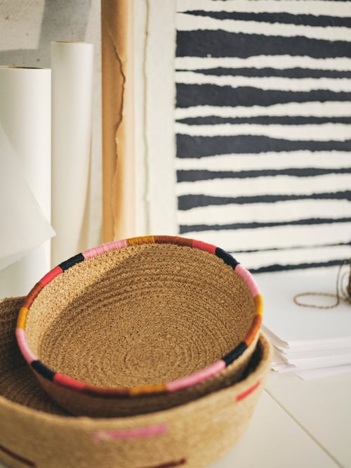 Living room featuring a round MÄVINN basket made of jute, holding a smaller round MÄVINN basket with the same design.