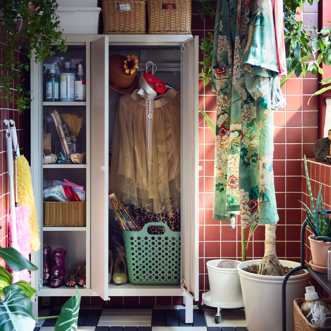A balcony with a beige KOLBJÖRN cabinet for storage, featuring baskets and cleaning supplies. Indoor plants are nearby.
