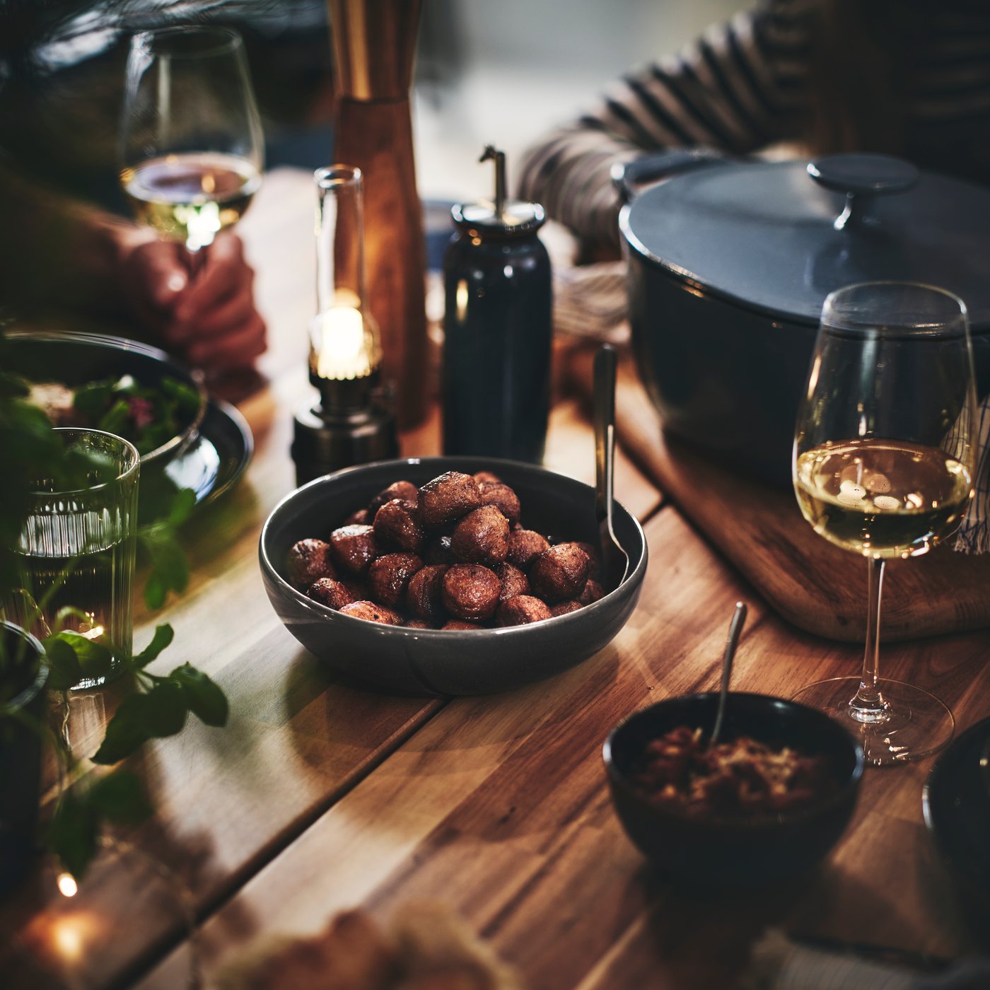 A GLADELIG bowl of HUVUDROLL plant balls on a dining table at a dinner party.