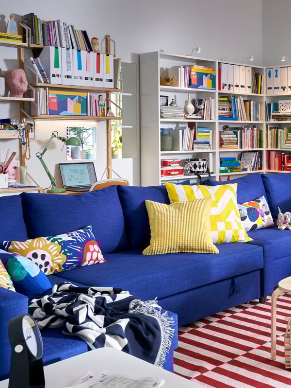 Blauw bank die in een woonkamer staat met veel felle kleuren.