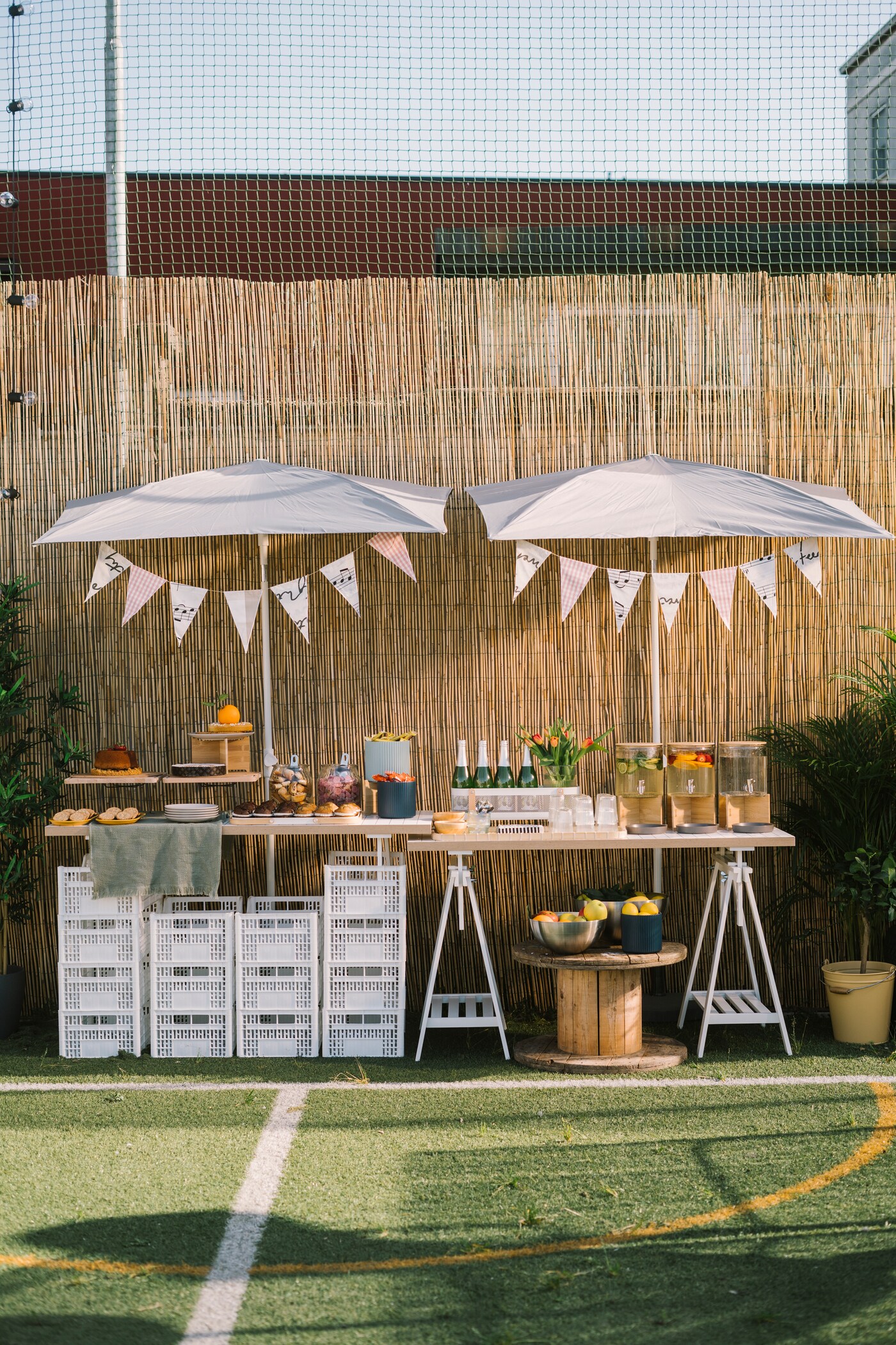 Un campo da gioco illuminato dal sole allestito con scrivanie LAGKAPTEN / MITTBACK e ombrelloni. Ci sono festoni, alimenti e bevande.