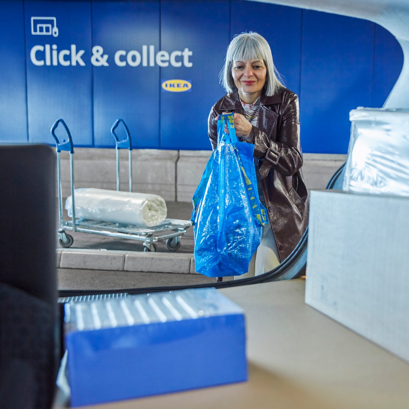 Woman putting click and collect purchases into the boot of her car