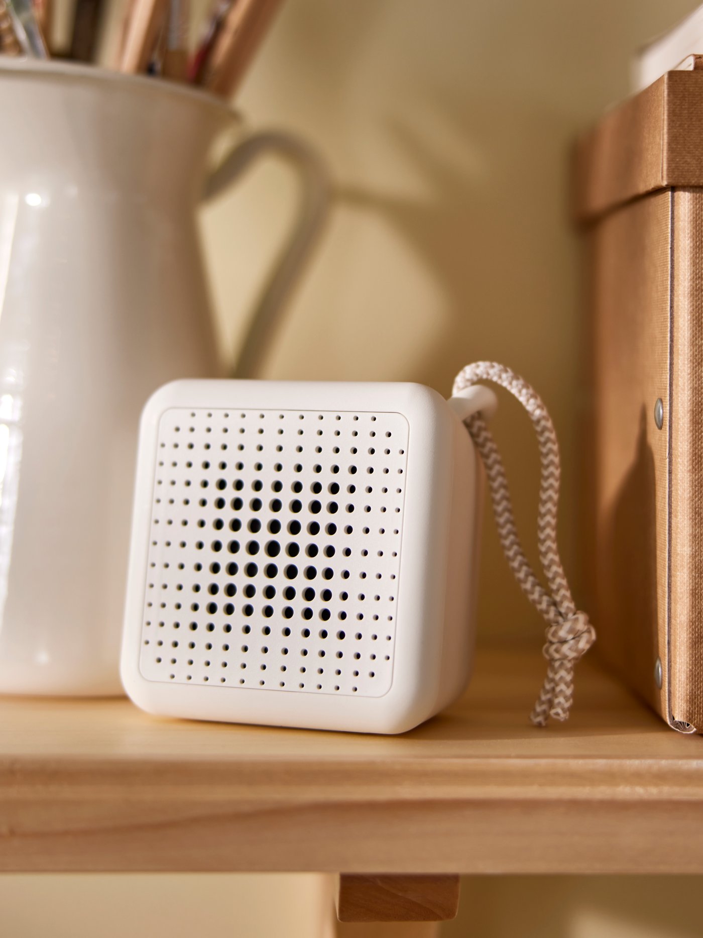 A VAPPEBY white bluetooth speaker next to a natural GÄRDESGÅRD storage box with lid