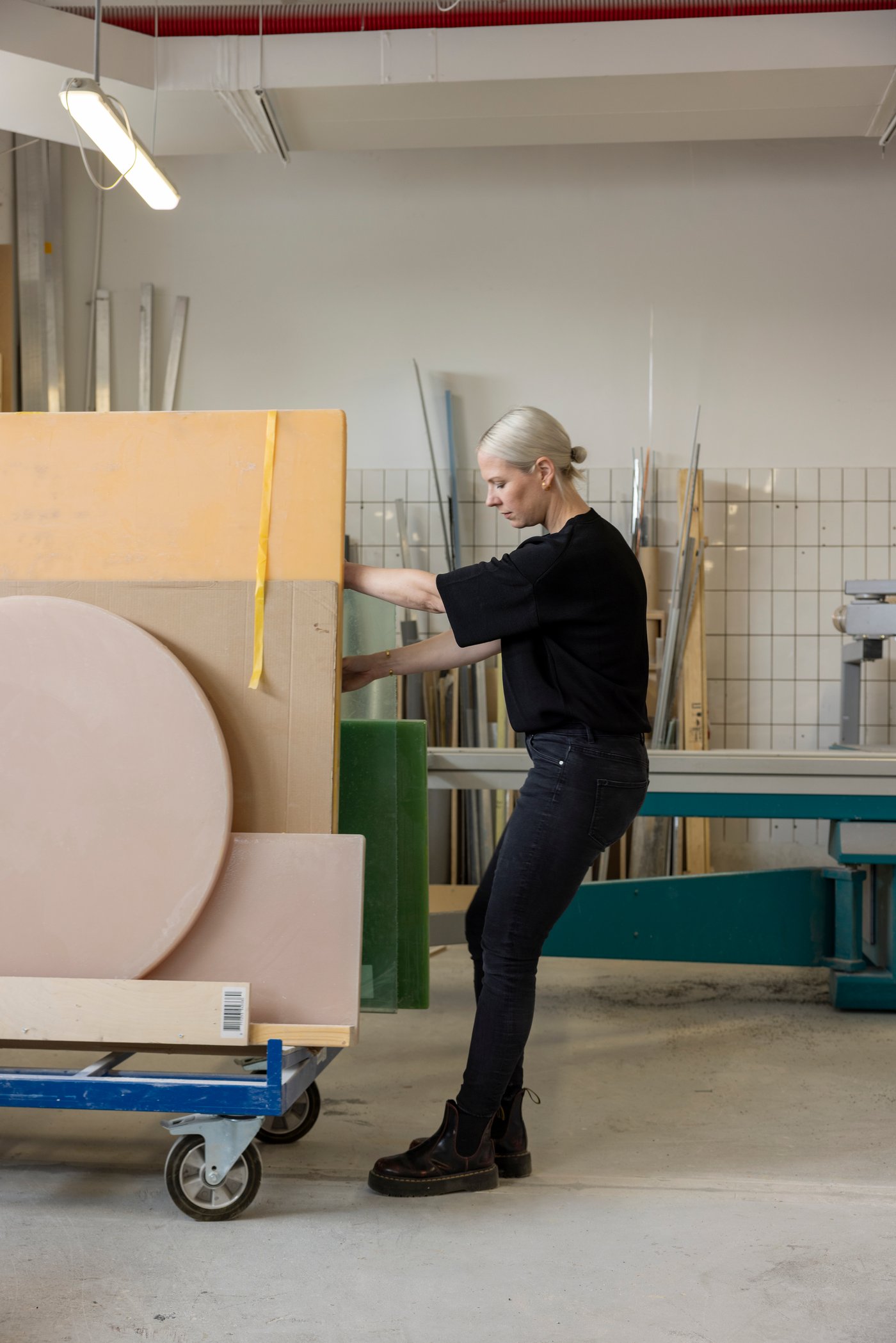 Designer Sabine Marcelis, dressed in black, pulls a trolley with sheets of resin and cardboard in her Rotterdam workshop.