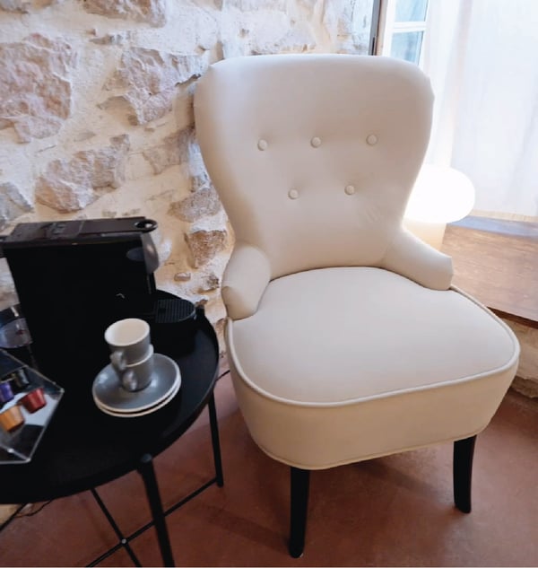 Fauteuil blanc dans un coin d'une pièce avec une table d'appoint sur le côté.