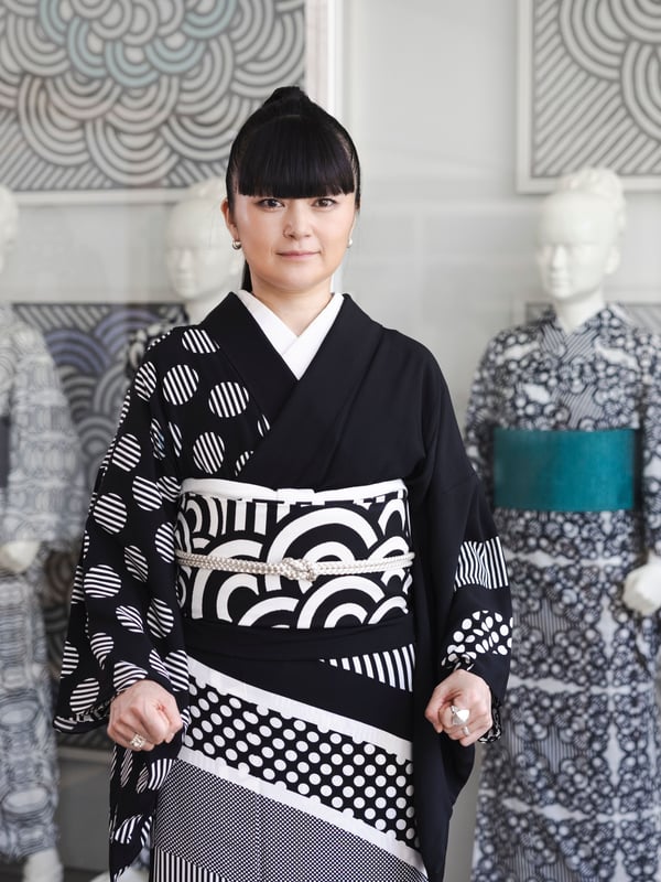 Designer Hiroko Takahashi standing in front of mannequins wearing kimonos in graphic patterns.